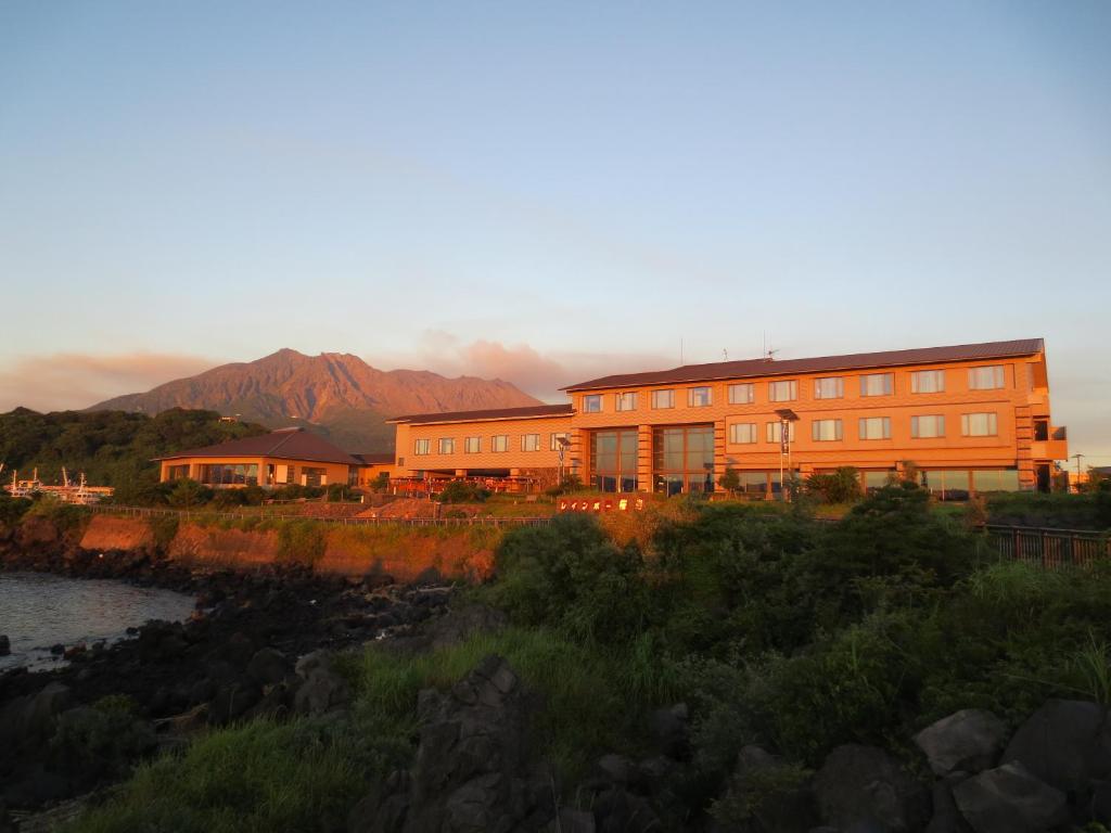 ein orangefarbenes Gebäude mit einem Berg im Hintergrund in der Unterkunft Rainbow Sakurajima in Sakurajima