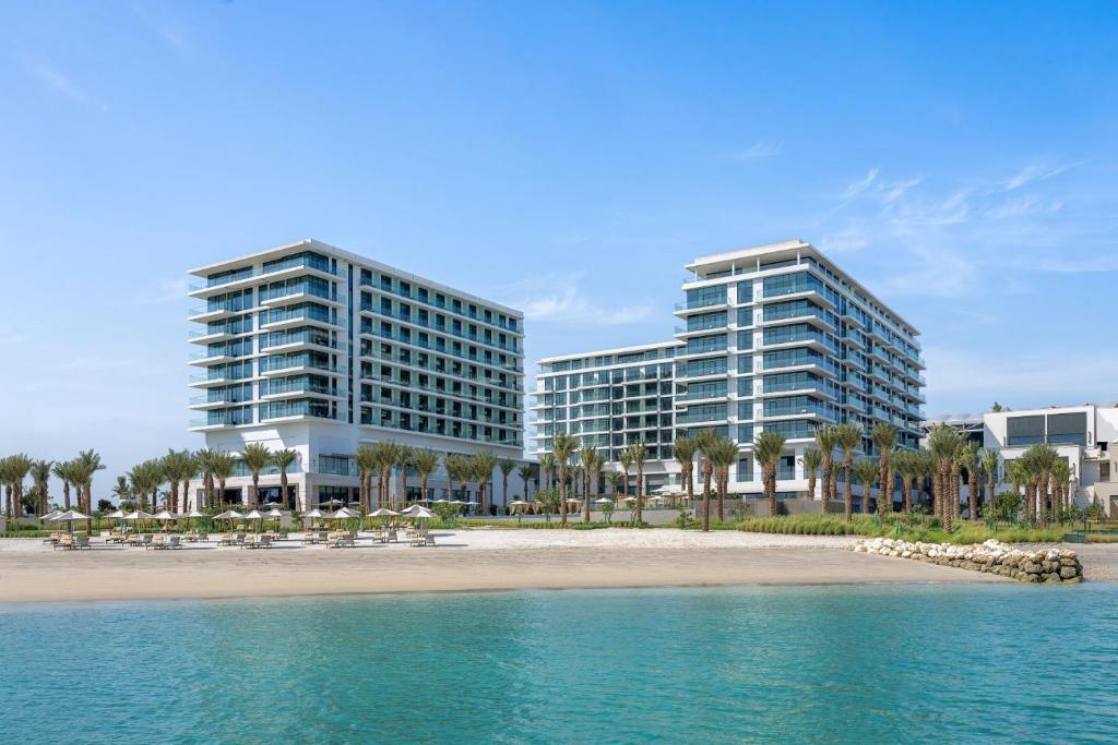 two tall buildings next to a beach with trees at Address Beach Resort Bahrain in Manama