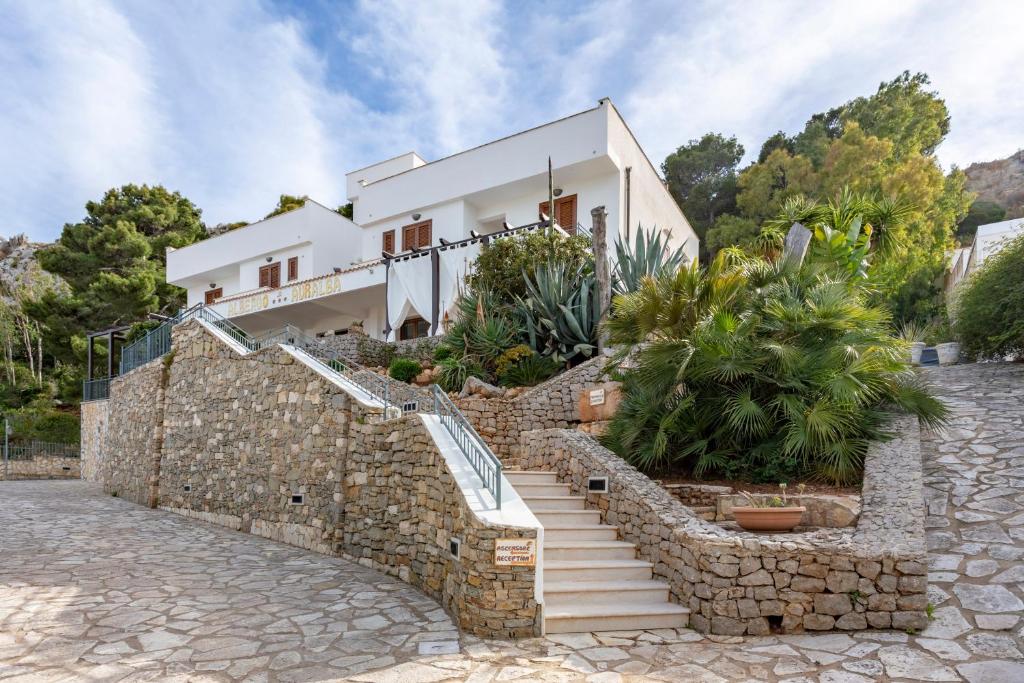 ein Haus mit einer Steinmauer und einer Treppe davor in der Unterkunft Albergo Auralba in San Vito lo Capo