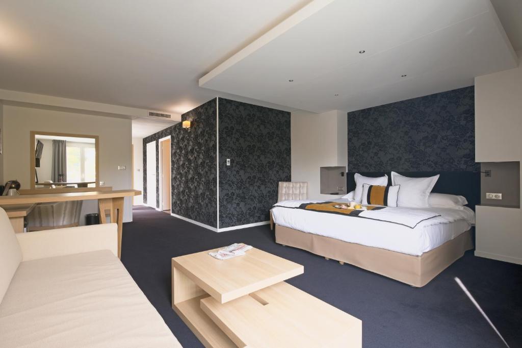モンソー・レ・ミーヌにあるLes Suites - Konine 4 - Hotel & Bar & Restaurantのベッドとデスクが備わるホテルルームです。