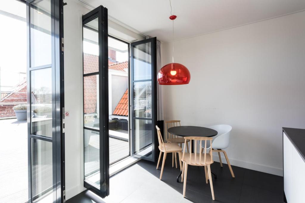 - une salle à manger avec une table, des chaises et des fenêtres dans l'établissement Hello Zeeland - Appartement Markt 4 en 4A, à Domburg