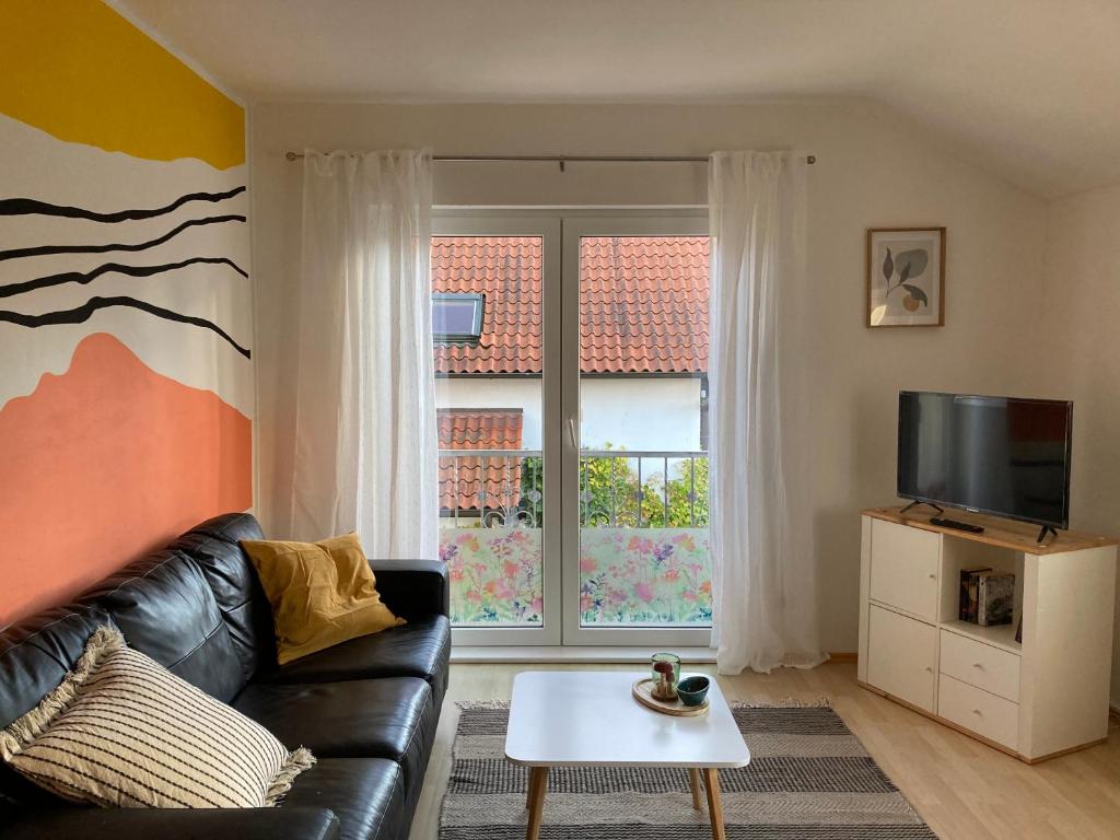 a living room with a black leather couch and a tv at Haus 51,8° in Bad Nenndorf