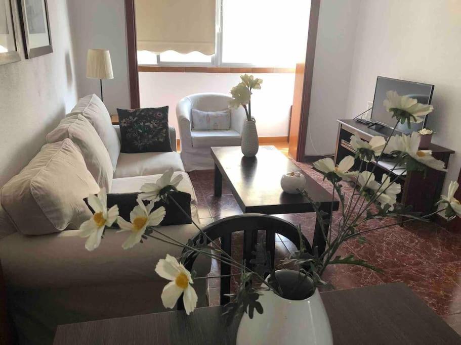 a living room with a couch and a table with flowers at Luminoso y acogedor in Las Palmas de Gran Canaria