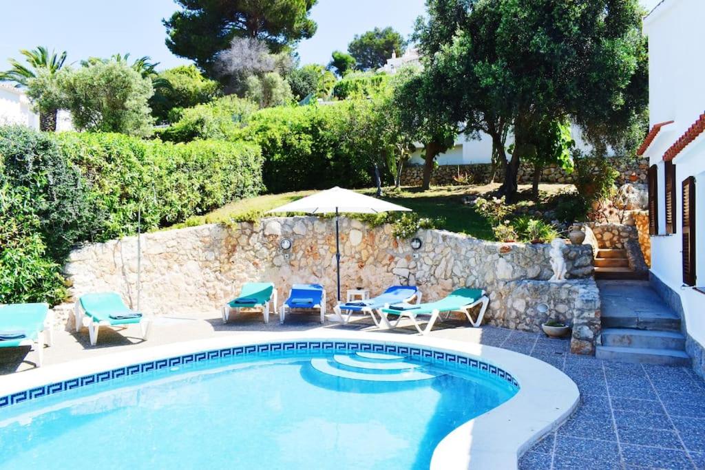 a swimming pool with chairs and an umbrella at VILLA MARIA vistas al mar y piscina privada in Son Bou