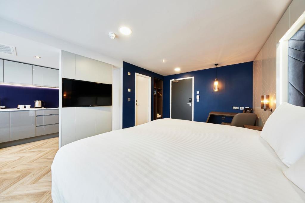 1 dormitorio con 1 cama blanca grande y paredes azules en Roomzzz Newcastle City, en Newcastle