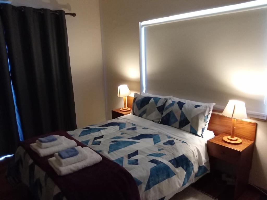 a bedroom with a blue and white bed with two lamps at 10 on Fairview B&B in Paarl
