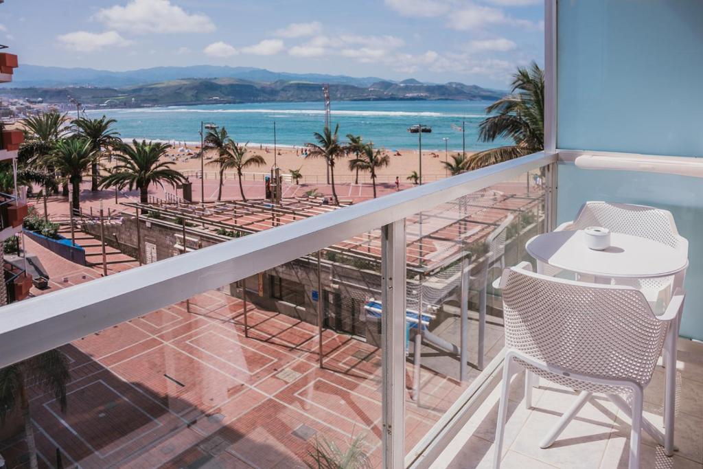 Un balcón con mesa y sillas y vista a la playa. en Hotel Aloe Canteras, en Las Palmas de Gran Canaria