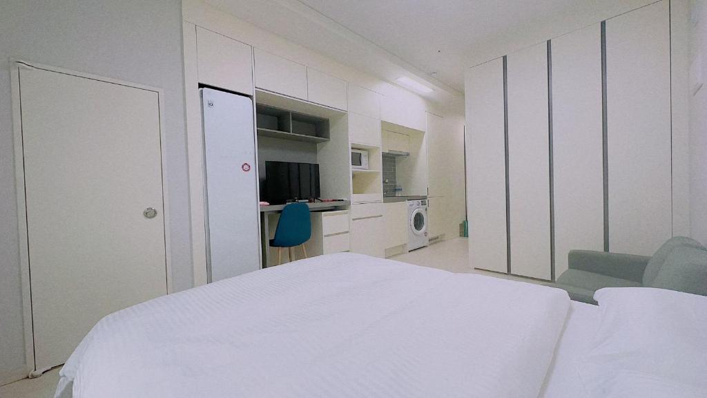 a white bedroom with a bed and a chair at THE TiME in Incheon
