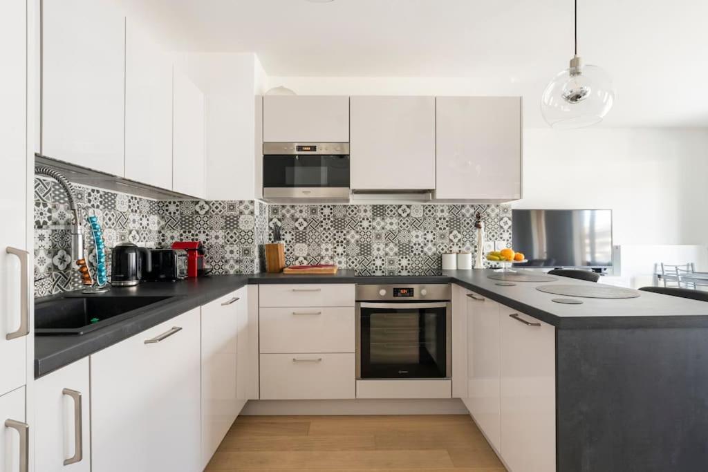 a kitchen with white cabinets and a black counter top at Flower Park - 10 mins by bus to Geneva Airport - Bus to Geneva, Palexpo, Arena, UN, CERN in Ferney-Voltaire