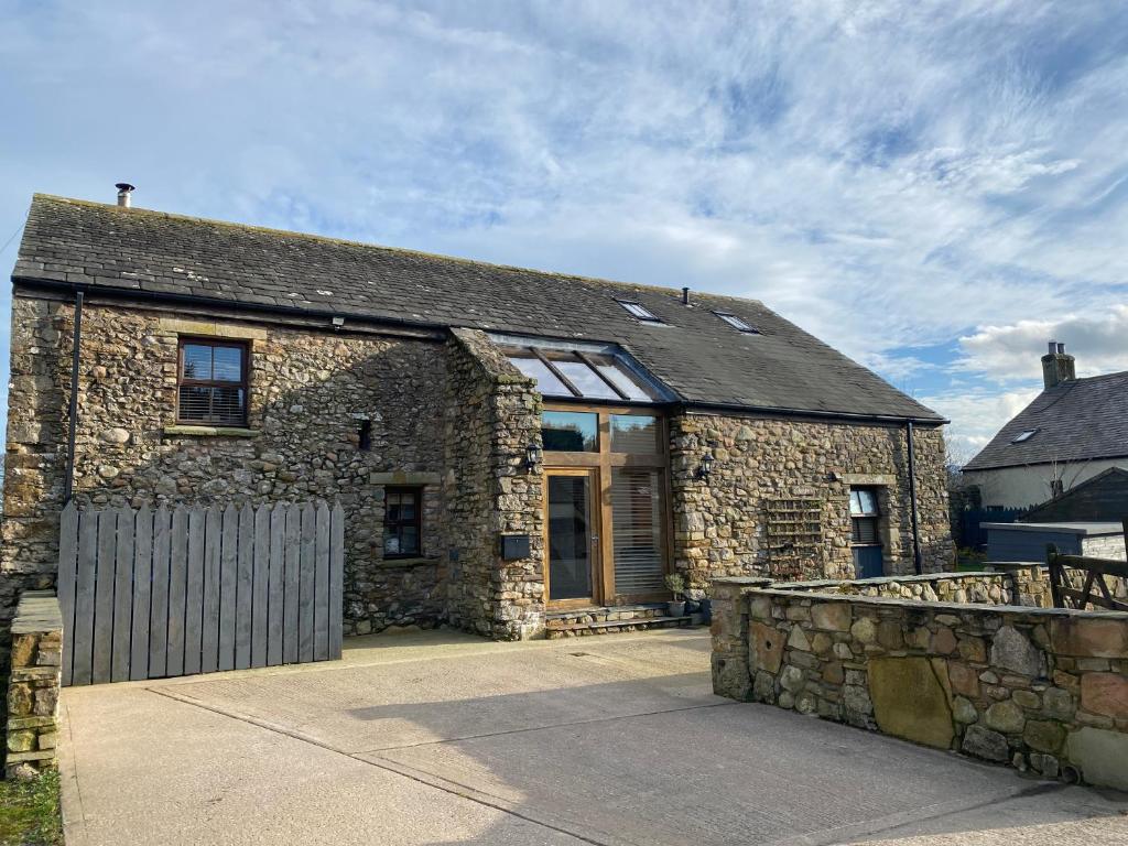 an old stone house with a stone wall at Swallow Barn in Cockermouth