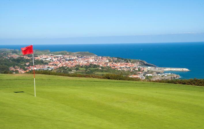 a golf course with a red flag on the green at Apartamentos Centro Llanes in Llanes