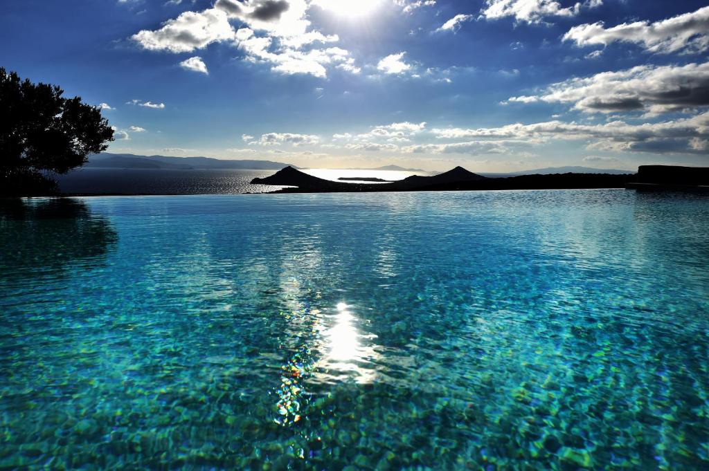 ein großer Wasserkörper mit der Sonne am Himmel in der Unterkunft Villa Acqua · Gorgeous pool villa, stunning sea views, helipad! in Parasporos