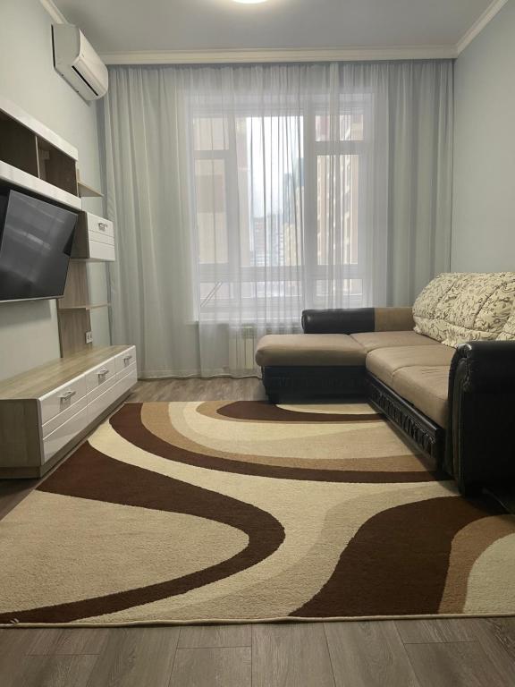 a living room with a couch and a large rug at Квартира в центре Нур-Султана in Astana