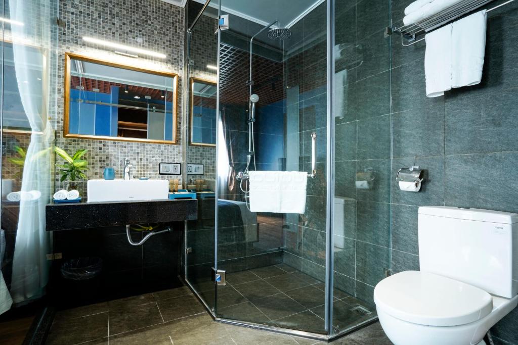 a bathroom with a toilet and a glass shower at 1925 Ha Long Hotel in Ha Long