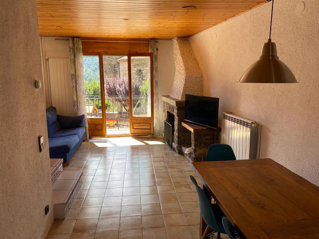 ein Wohnzimmer mit einem Tisch und einem Kamin in der Unterkunft Cal Carbassó in Pardines