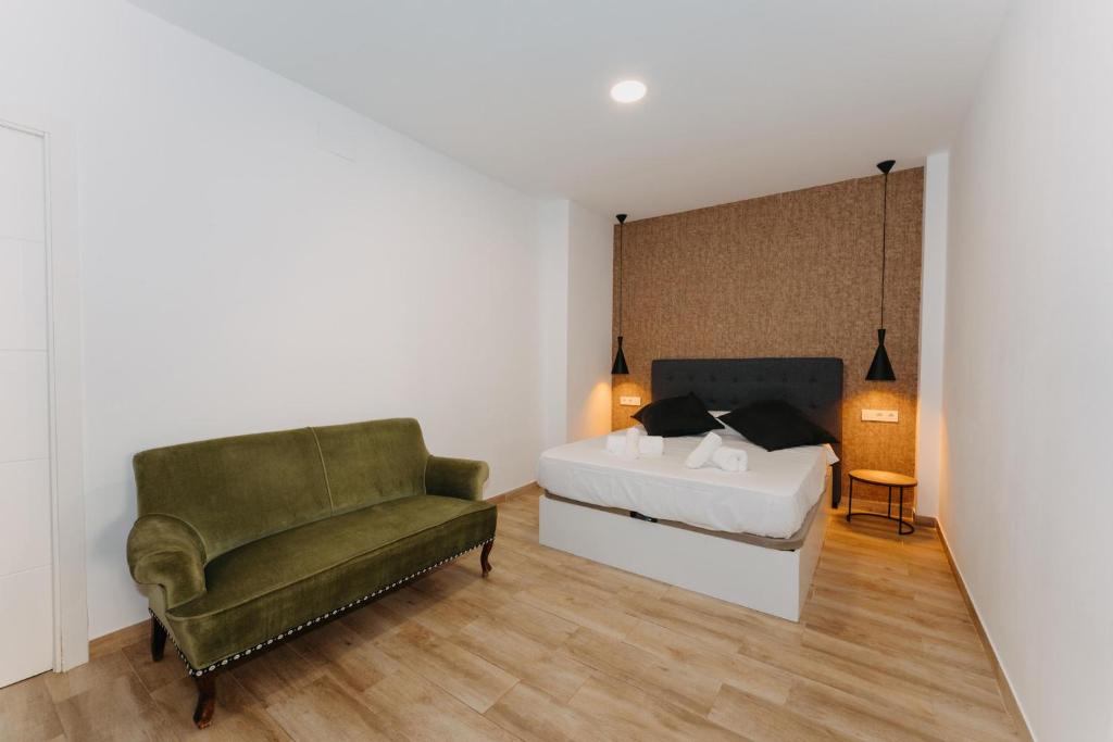 um quarto com uma cama e uma cadeira verde em Coverlin Apartamentos San Francisco em Málaga