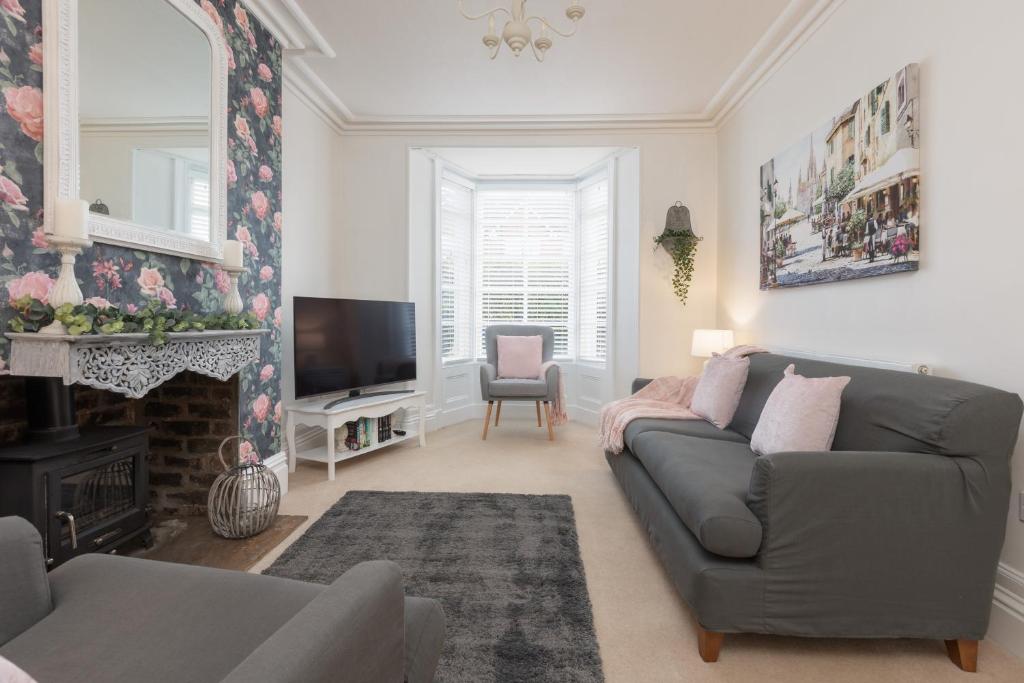 un soggiorno con divano grigio e camino di Charles Alexander Short Stay - Rose Cottage a Lytham St Annes