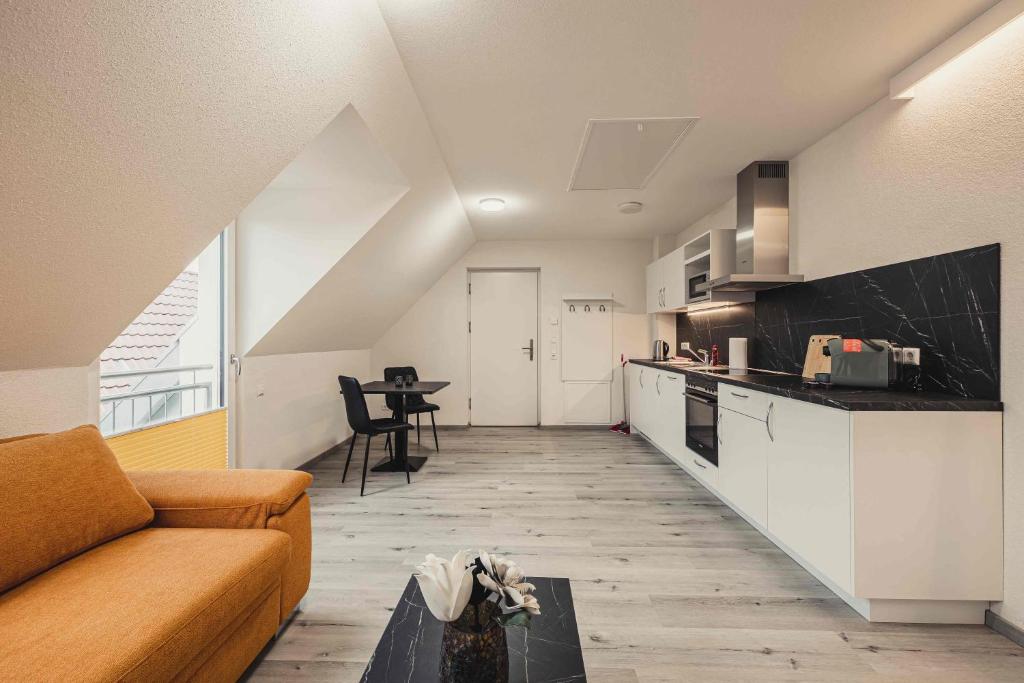 ein Wohnzimmer mit einem Sofa und einer Küche in der Unterkunft Ferienwohnungen und Boardinghouse Heimbach in Renchen in Renchen