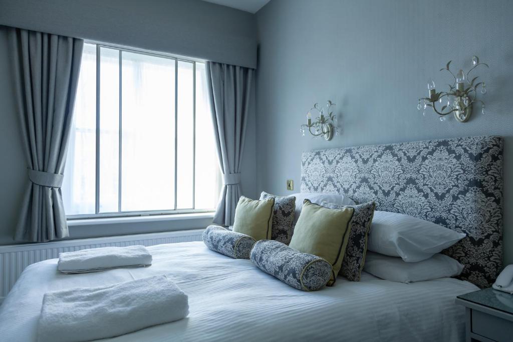a bedroom with a bed with pillows and a window at The Royal Hotel in Ventnor