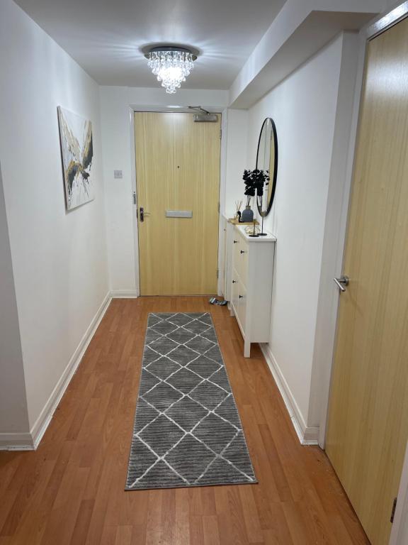 a hallway with a wooden door and a rug at Entire 2 bedroom Beautiful newly furnished flat in Glasgow