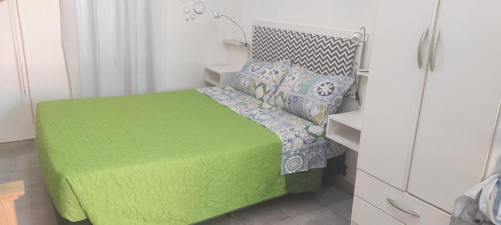 a small bedroom with a green bed with pillows at hospedaje aeropuerto Ezeiza Mascotas tranfer gratis al aeropuerto de Ezeiza a 20 minutos in Ezeiza