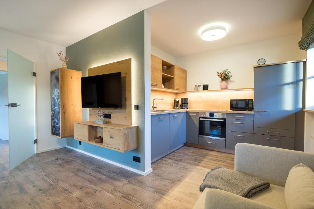 uma cozinha com armários azuis e uma televisão num quarto em Ferienwohnung Alpentraum - Wildblume em Fischen