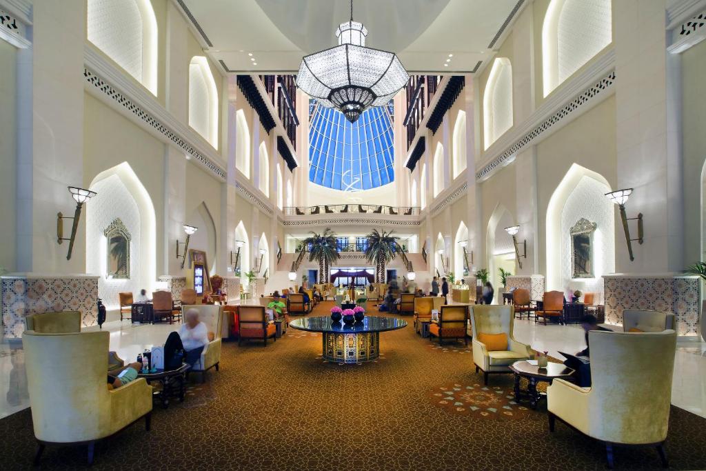 um lobby com pessoas sentadas em cadeiras em um edifício em Bab Al Qasr Hotel em Abu Dhabi