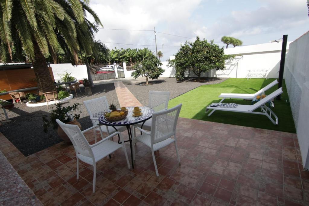 un patio con mesa, sillas y césped en VV Casita El Paraíso en Breña Baja