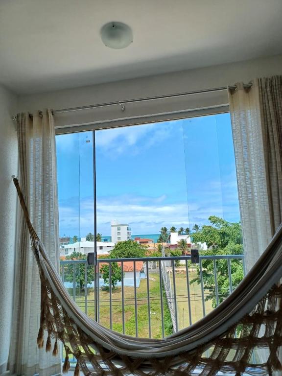 a hammock in a room with a large window at Apartamento em Camboinha in João Pessoa