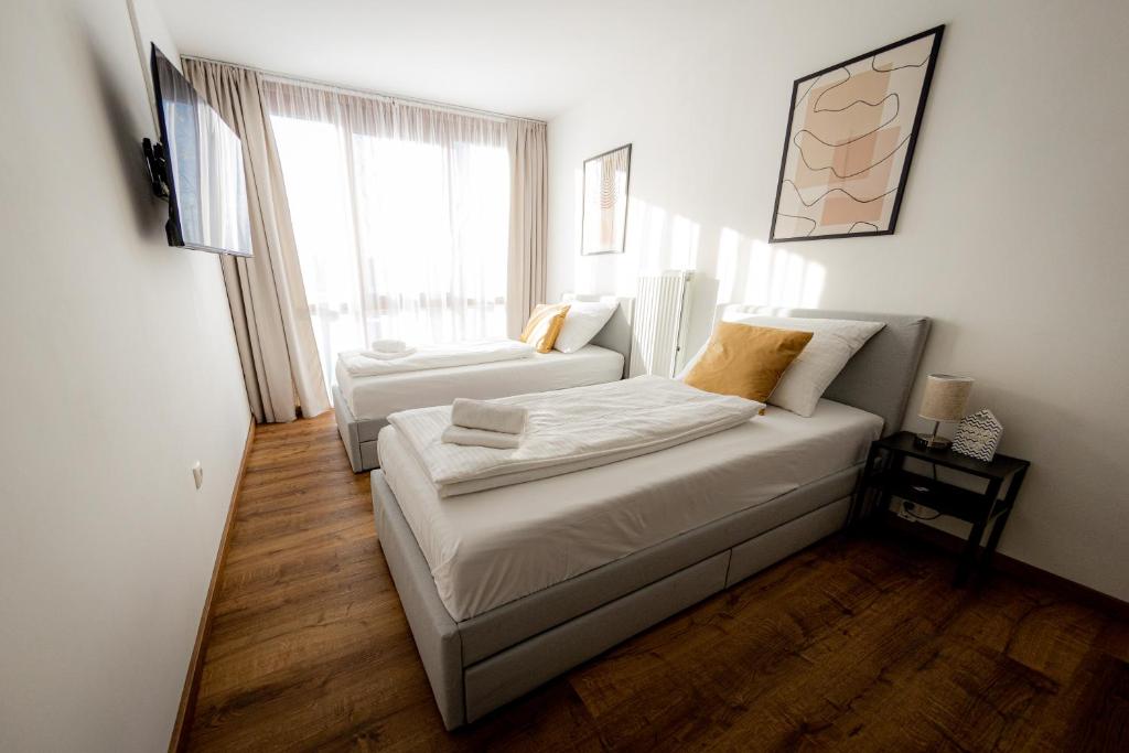 a bedroom with two beds and a large window at Come4Stay Passau - Holzheim 411 I modern I WLAN I Küche I Parkplatz I SmartTV mit Netflix in Passau