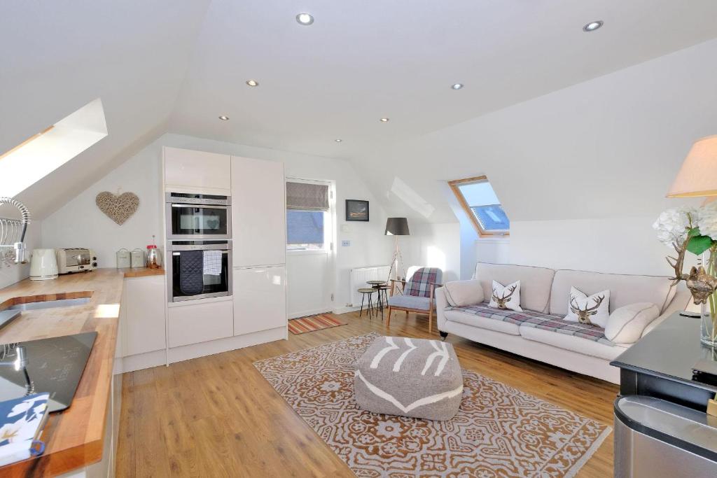 a white living room with a couch and a kitchen at The Loft in Stonehaven