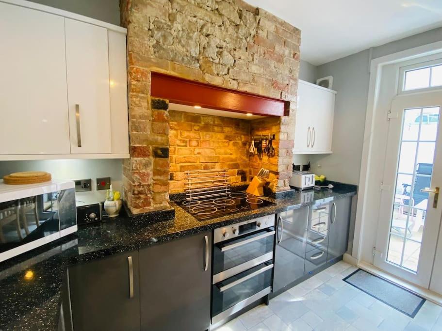 a kitchen with a brick wall and a stove top oven at Green Sails House in Weymouth