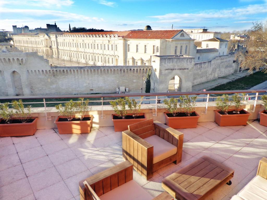 uma varanda com bancos e vista para a cidade em ApartHotel Sainte-Marthe em Avignon