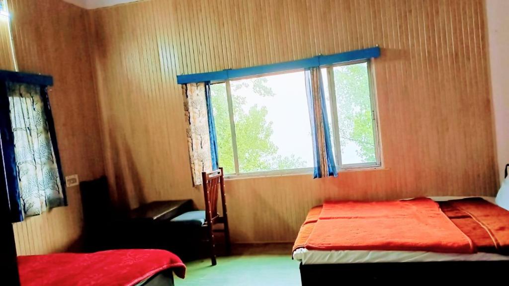 um quarto com uma cama, uma janela e uma cadeira em The HappyTel em Mussoorie