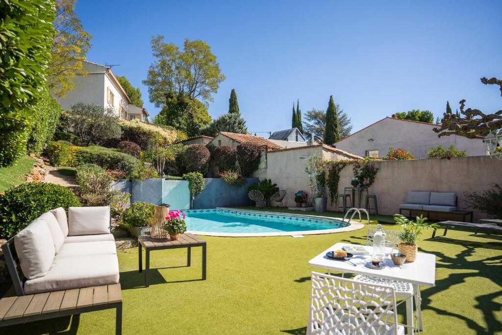 a backyard with a swimming pool and green grass at Logis Hôtel La Fenière in La Bouilladisse