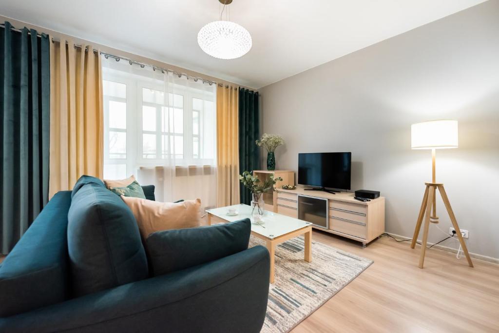 sala de estar con sofá azul y TV en Metro Stokłosy Blue Mint Apartment, en Varsovia