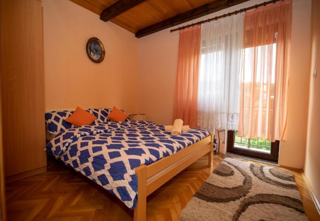 sypialnia z łóżkiem z pomarańczowymi poduszkami i oknem w obiekcie Holiday Home Lana w mieście Fužine