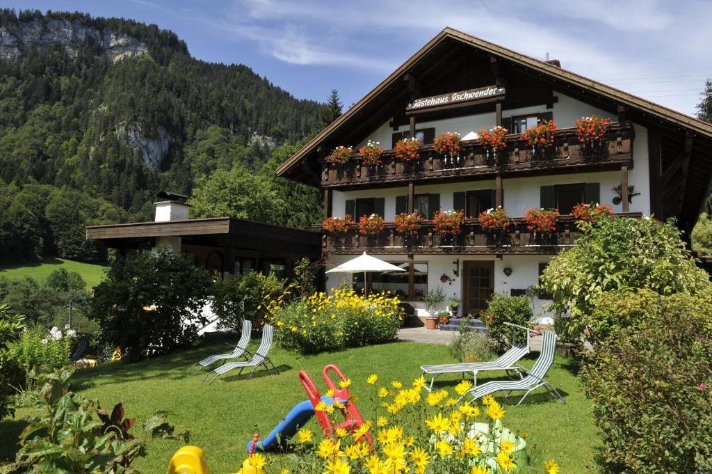 ein Gebäude mit einem Garten mit Stühlen und Blumen in der Unterkunft Gschwenderhaus Ferienwohnungen in Oberstdorf