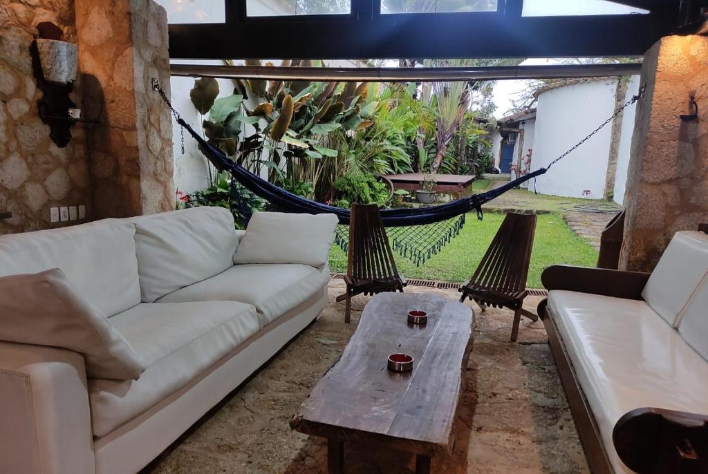 a living room with a couch and a hammock at Casa rústica centenária no Centro Histórico de Paraty - Wifi 120MB in Paraty