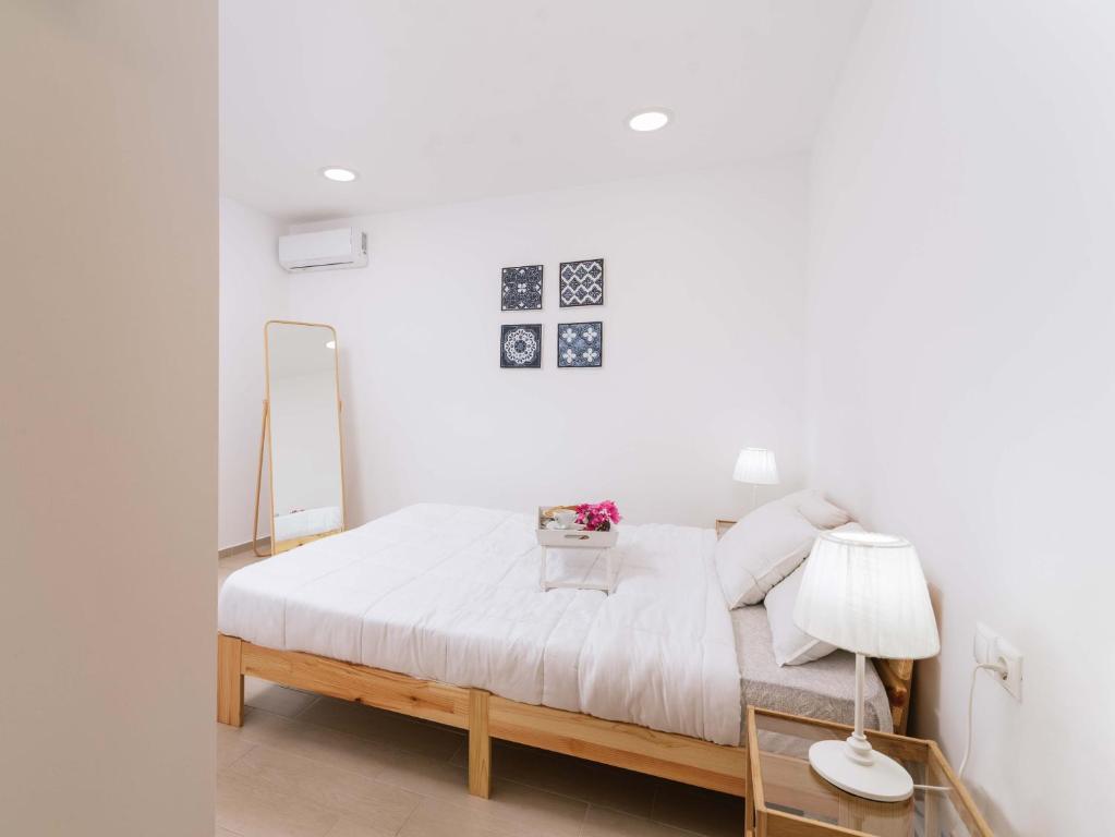 a white bedroom with a bed and a mirror at Nikkon summer home in Matala
