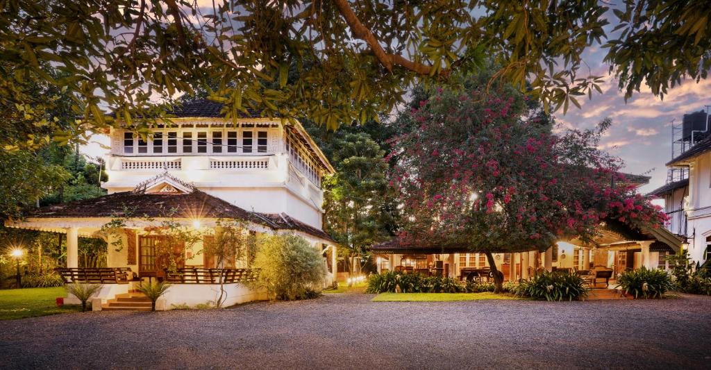 un grande edificio bianco con un albero di fronte di MAI HOUSE HERITAGE HOTEL a Fort Kochi