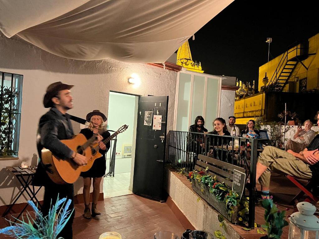 un hombre tocando una guitarra delante de una multitud de personas en San Isidoro Hostel Sevilla, en Sevilla