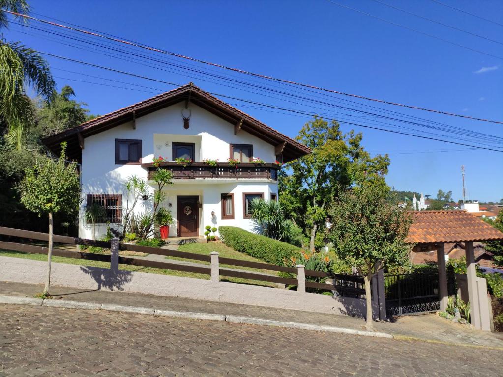 une maison blanche avec une clôture devant elle dans l'établissement Hospedaria Hartmann Haus, à Treze Tílias