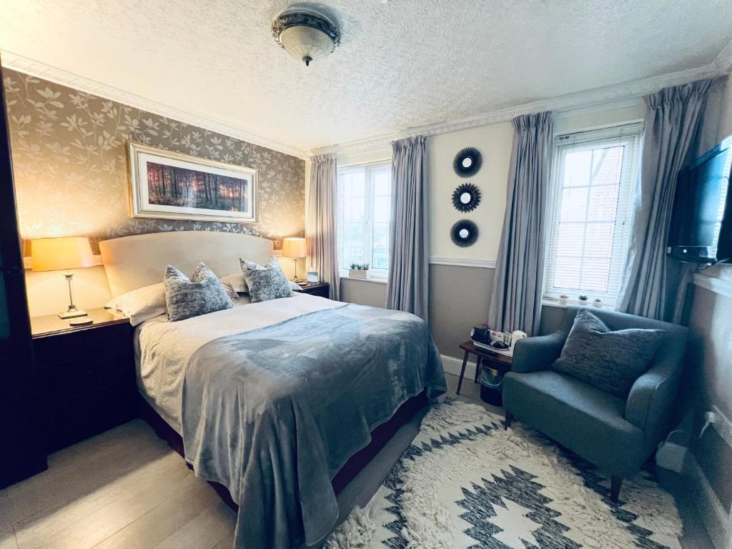 a bedroom with a bed and a chair and windows at Ashleigh House in Carlisle