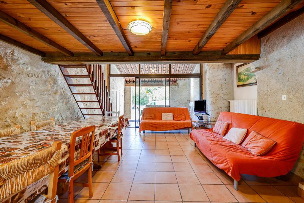 een woonkamer met een lange tafel en een oranje bank bij Maison de 3 chambres avec piscine partagee terrasse amenagee et wifi a Lagrasse in Lagrasse