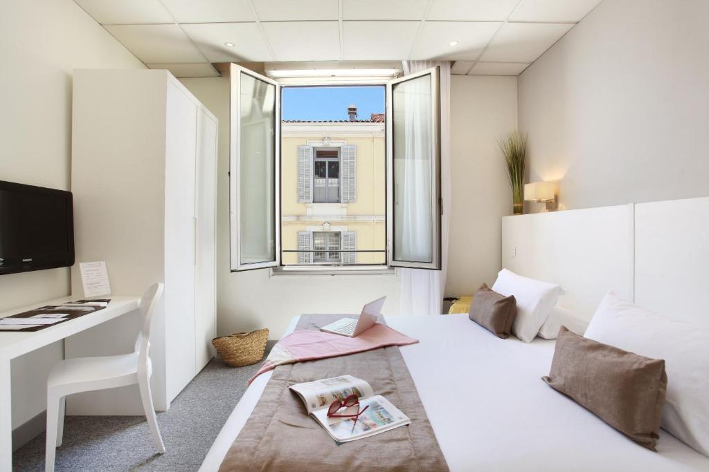a bedroom with a bed and a desk and a window at Hôtel P.L.M. in Cannes