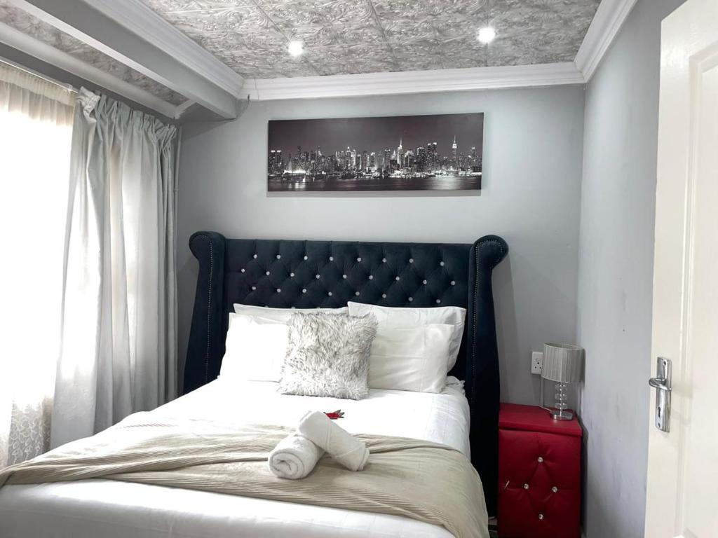 a bed with a black headboard in a bedroom at amazing grace guesthouse in East London