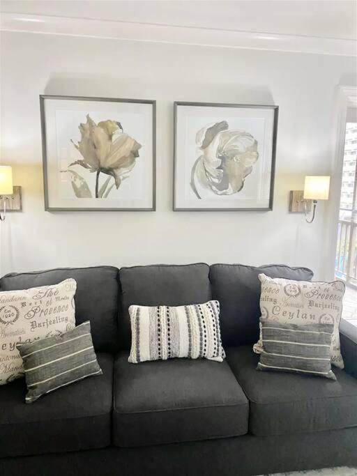 a black couch in a living room with three pictures on the wall at Downtown! 24h Concierge! Private Balcony! Highrise Views in Atlanta