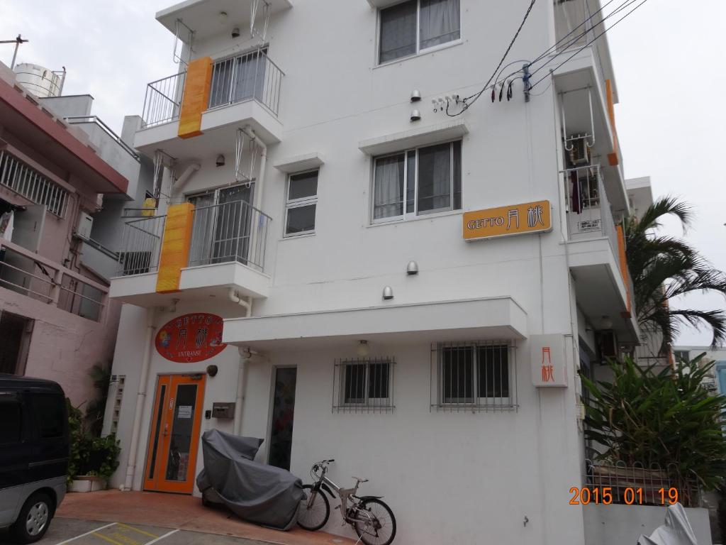 un edificio blanco con una bicicleta estacionada frente a él en Minshuku Getto en Naha