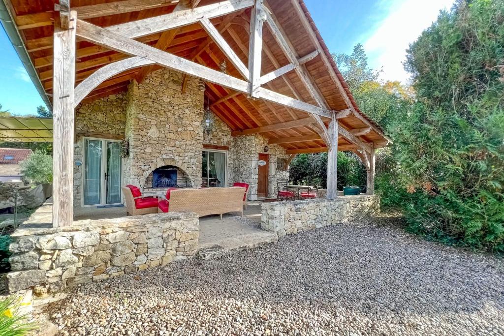 a stone house with a wooden roof and a fireplace at Beautiful guest house for two people on the bank of the Dordogne river in Siorac-en-Périgord